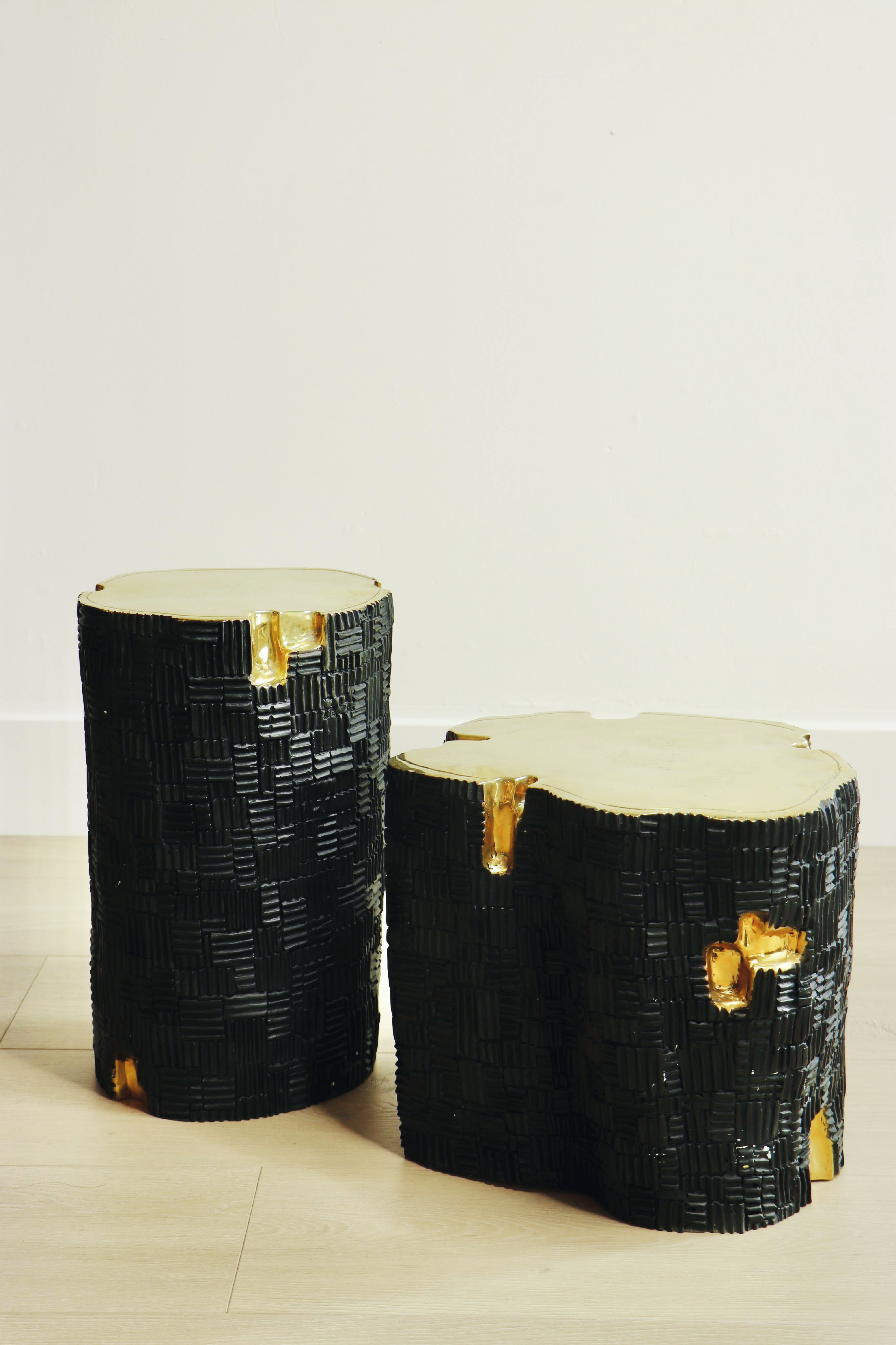 Two black and gold brass furniture side tables on a light wooden floor.