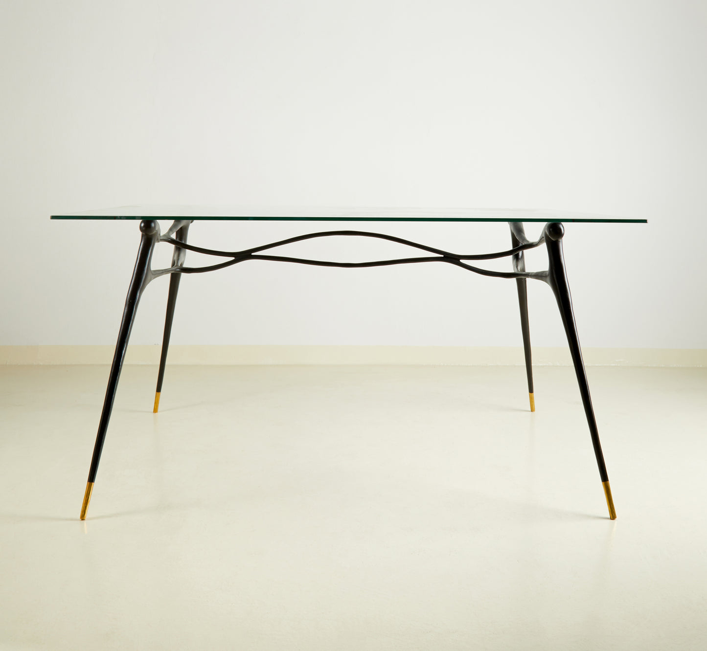 Glass table with black brass  base on a wooden floor