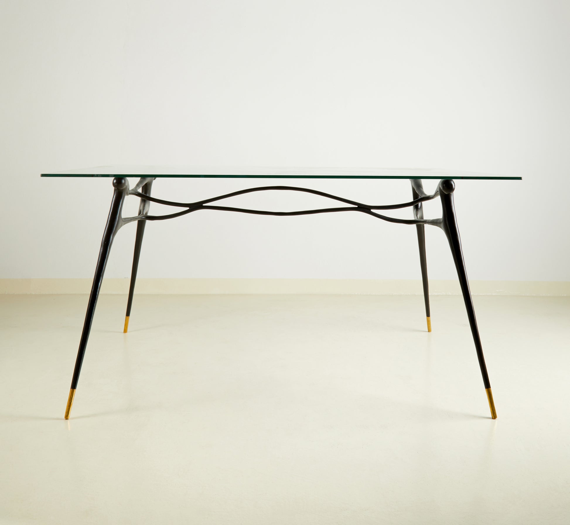 Glass table with black brass  base on a wooden floor