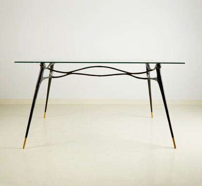 Glass table with black brass  base on a wooden floor