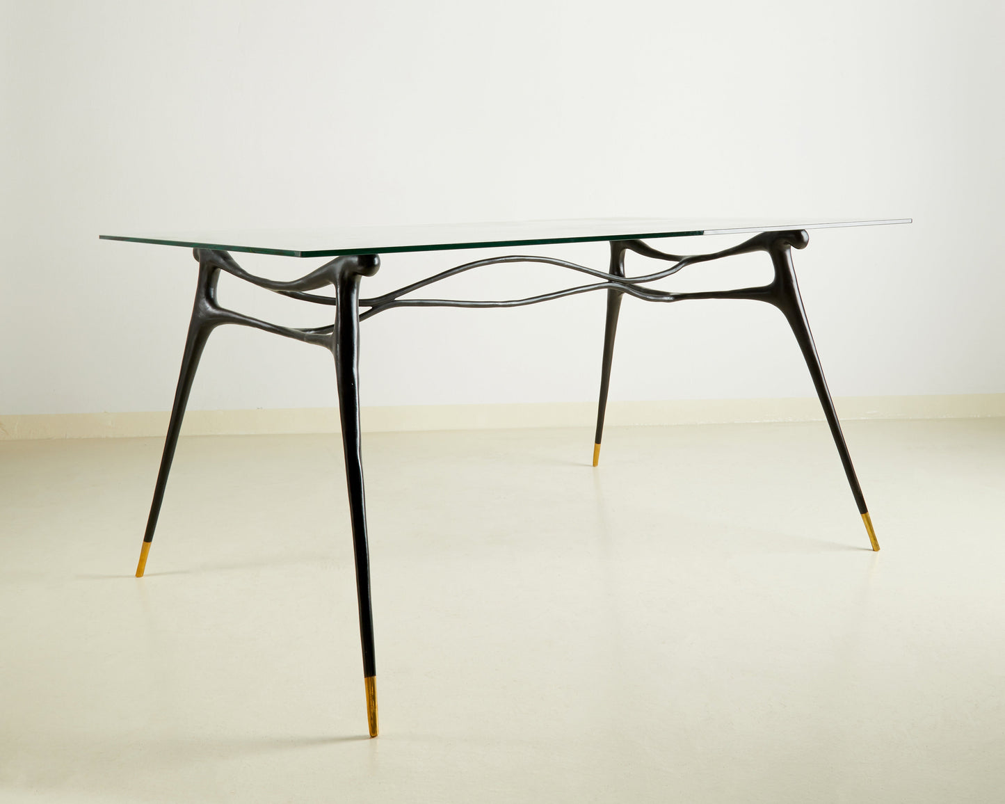 Glass table with black brass  base on a wooden floor