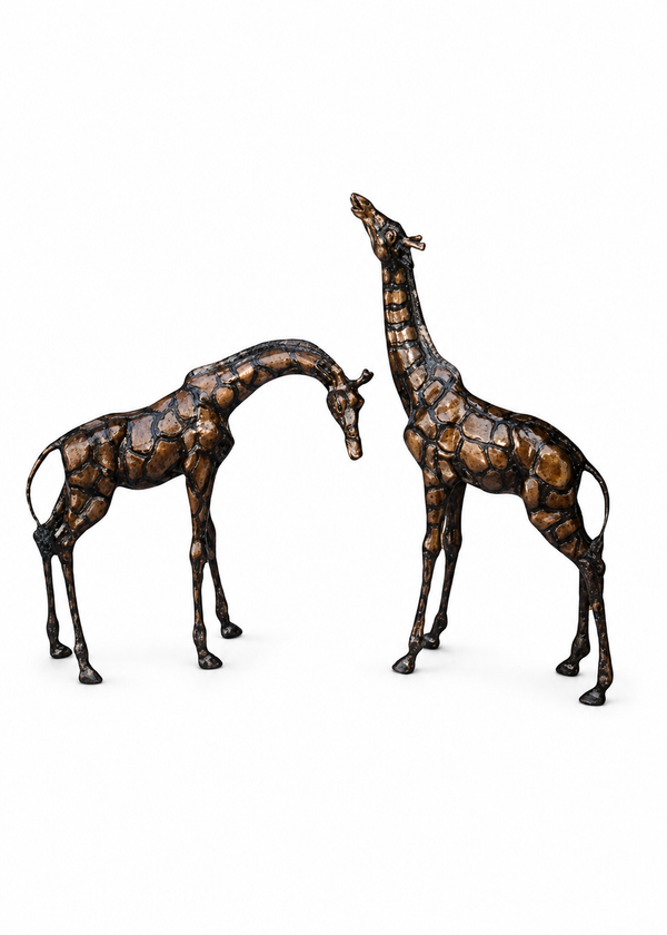 Two bronze giraffe sculptures standing on a white background, one facing left with head bowed and the other facing right with head raised.