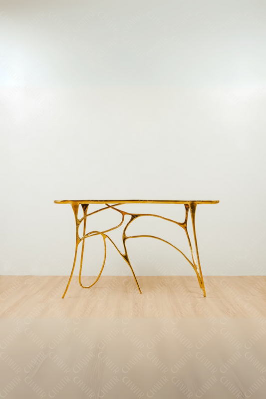 Gold brass luxury handmade furniture table with organic design, perfect for modern luxury decor, on a light wooden floor with white wall background.