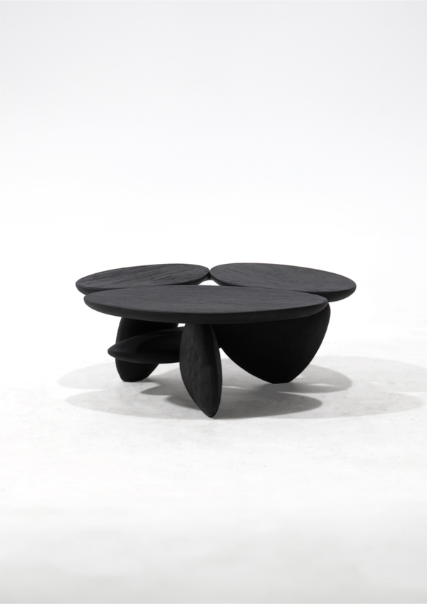 A modern black sculptural coffee table with a rounded, organic shape and three distinct pedestal legs, photographed on a seamless white studio background.
