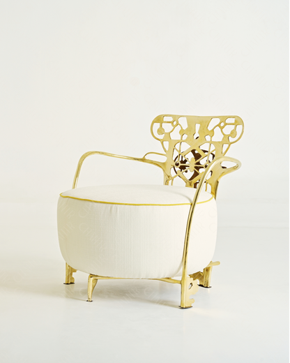 Gold lounge chair with white cushion with intricate backrest design on a light gray background. Luxury handmade furniture