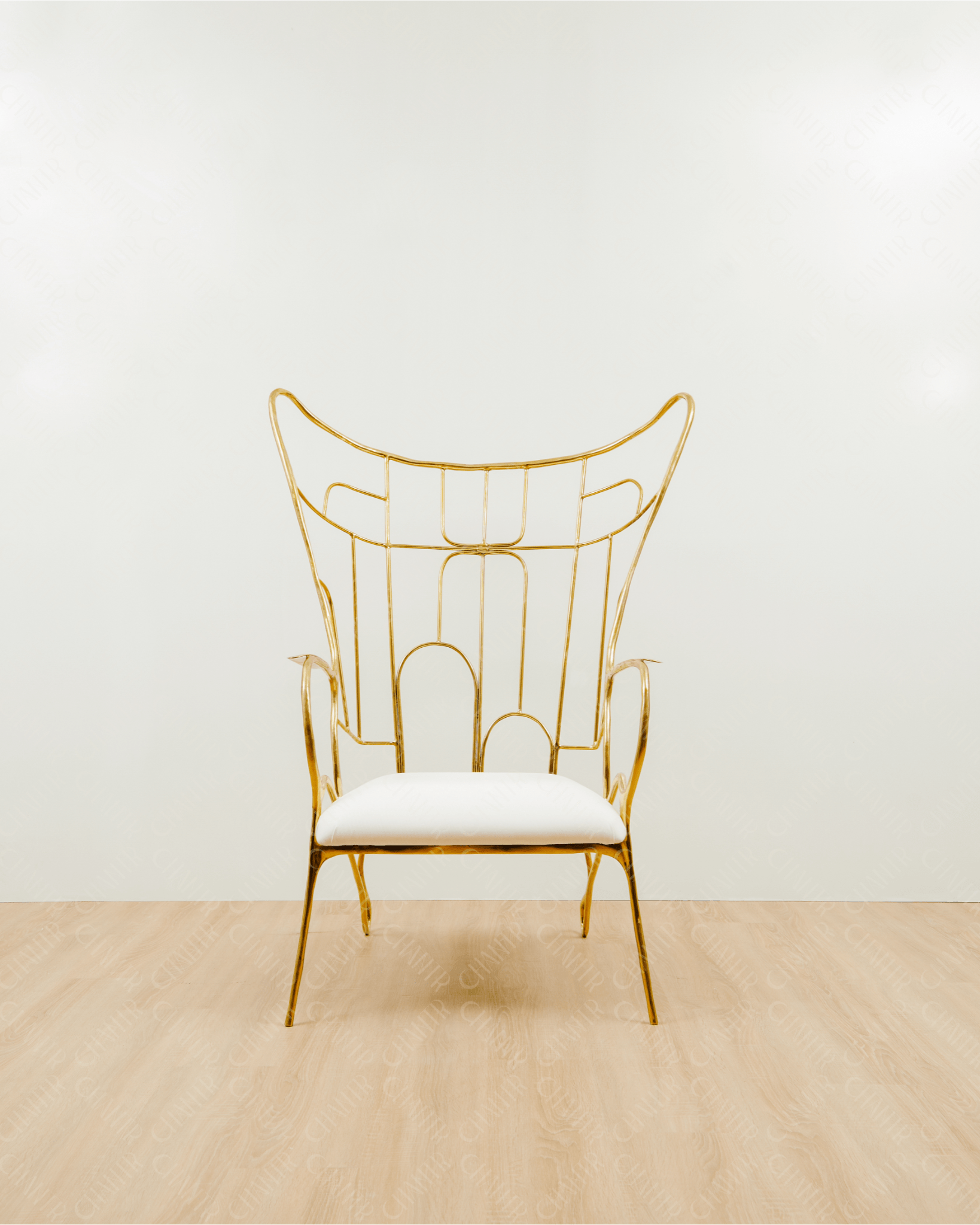 Gold brass luxury handmade furniture chair with white cushion on a light wooden floor, paired with a gold brass side table topped with a white vase, perfect for modern luxury decor. Straight angle