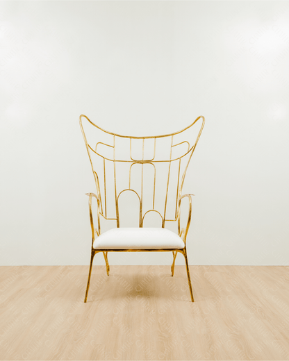 Gold brass luxury handmade furniture chair with white cushion on a light wooden floor, paired with a gold brass side table topped with a white vase, perfect for modern luxury decor. Straight angle