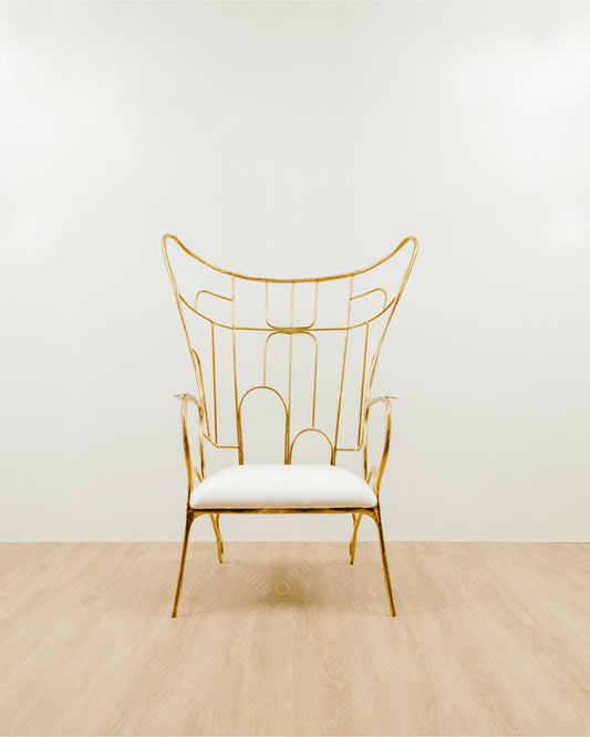 Gold brass luxury handmade furniture chair with white cushion on a light wooden floor, paired with a gold brass side table topped with a white vase, perfect for modern luxury decor. Straight angle