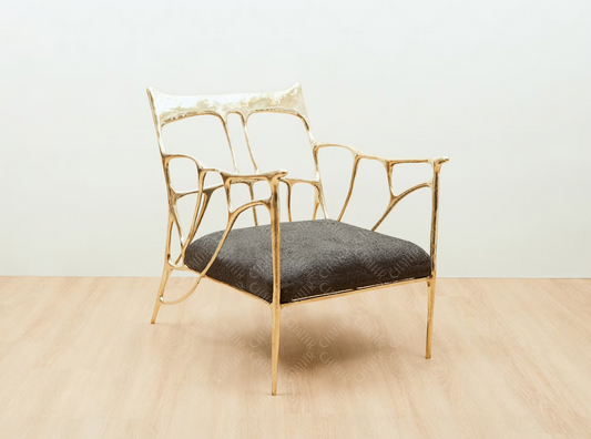 Gold brass luxury handmade furniture armchair with textured gray cushion, ideal for modern luxury decor, on a beige floor with white wall background. Side angle