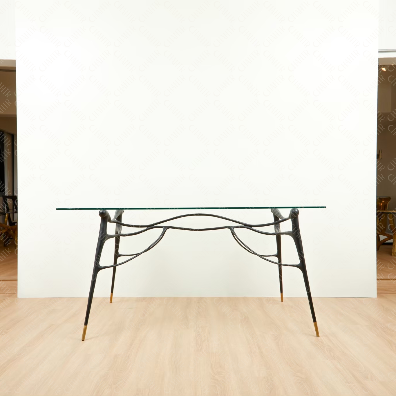 Glass table with black brass  base on a wooden floor