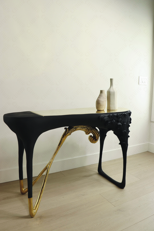 Black console table with gold brass accents, luxury handmade furniture, styled with two vases, perfect for modern luxury decor, against a white wall.