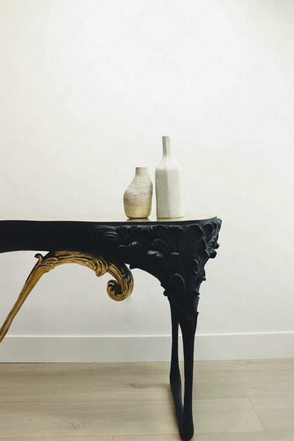 Zoomed in - Black console table with gold brass accents, luxury handmade furniture, styled with two vases, perfect for modern luxury decor, against a white wall.