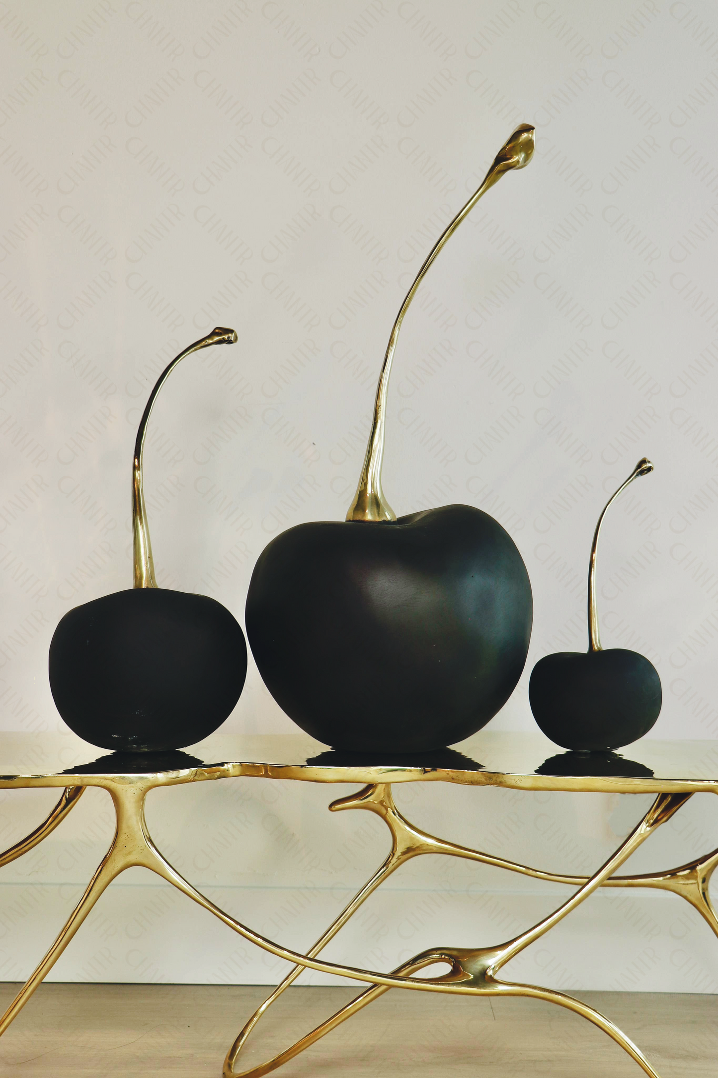 Luxury handmade furniture: Modern luxury decor of Black cherries with gold stems on a brass furniture bench. 