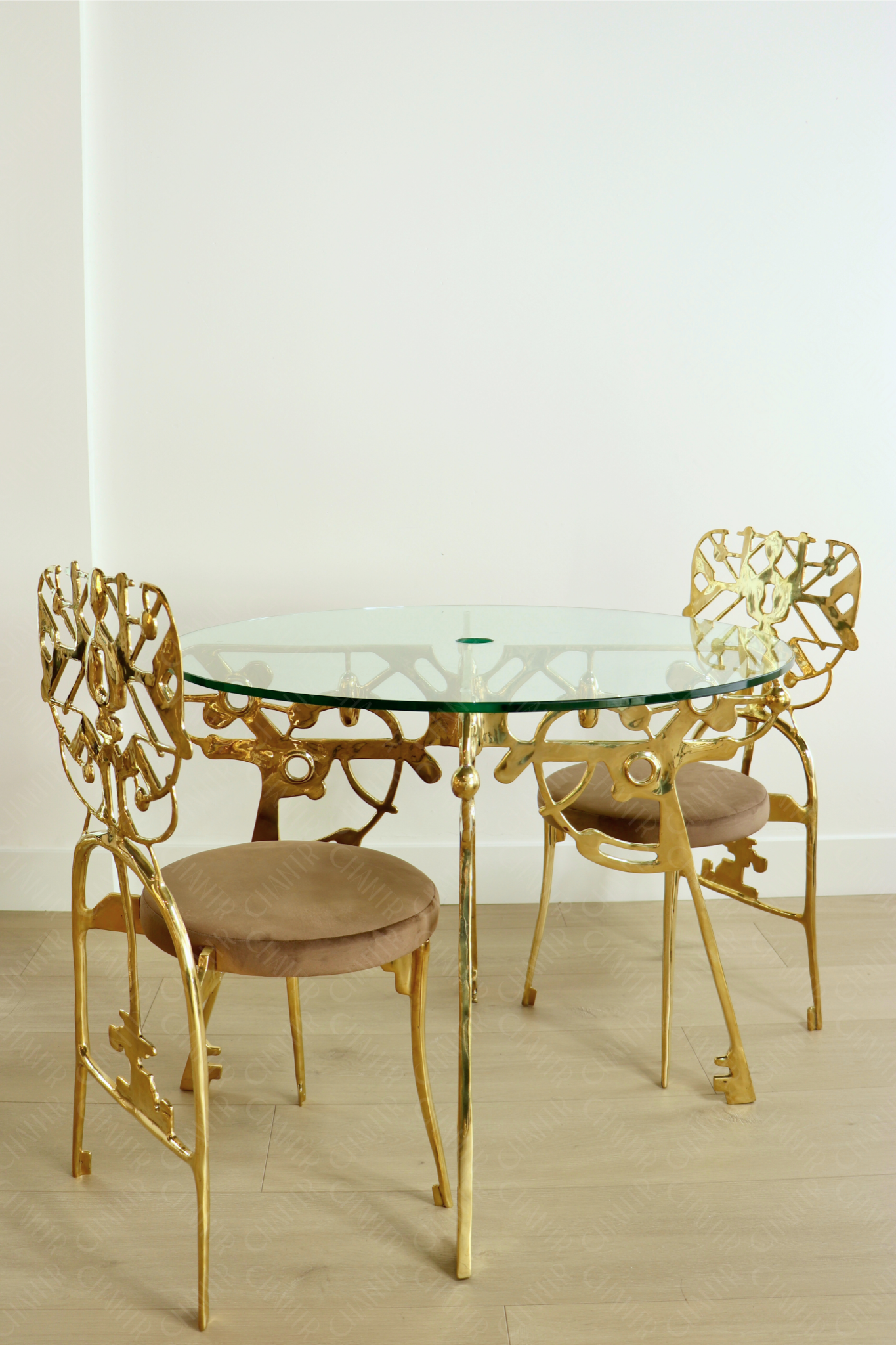 Gold dining set with glass table and chairs on a light wooden floor. Luxury handmade furniture