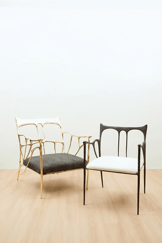 Two chairs, one with gold frame and black cushion, the other with black frame and white cushion, on a light wooden floor. Luxury handmade furniture