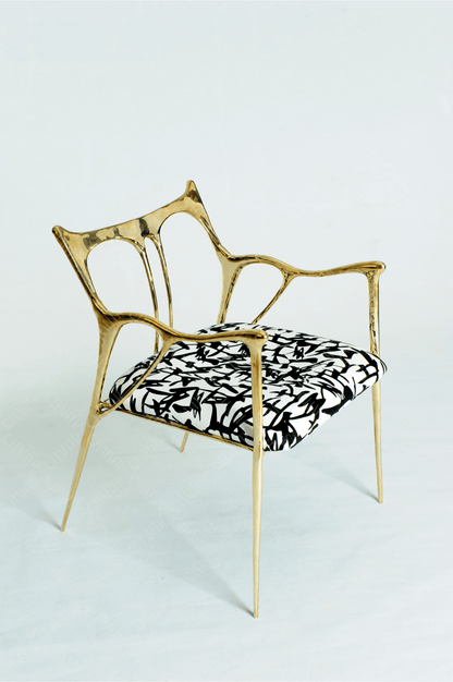 Gold brass luxury handmade furniture chair with patterned cushion, ideal for modern luxury decor, on a wooden floor.