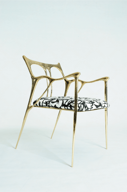 Gold brass luxury handmade furniture chair with patterned cushion, ideal for modern luxury decor, on a wooden floor.