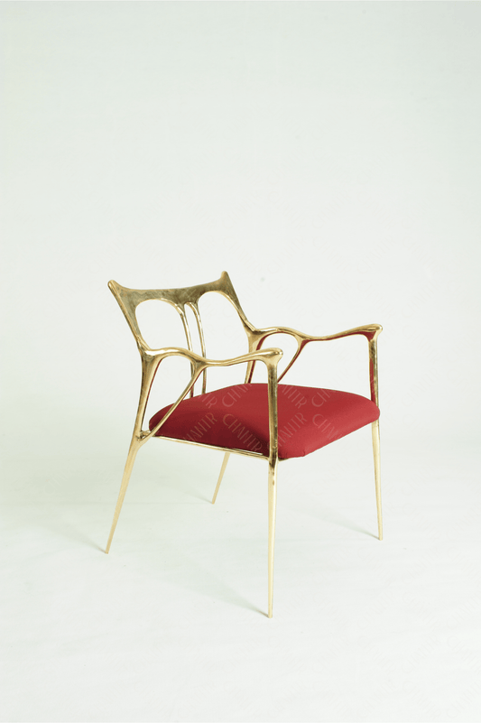 Gold brass luxury handmade furniture chair with red cushion, ideal for modern luxury decor, on a wooden floor.