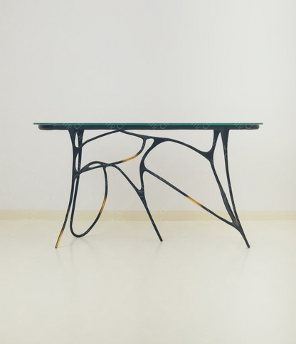 Black brass luxury handmade furniture table with organic design and glass top, perfect for modern luxury decor, on a light wooden floor with white wall background.
