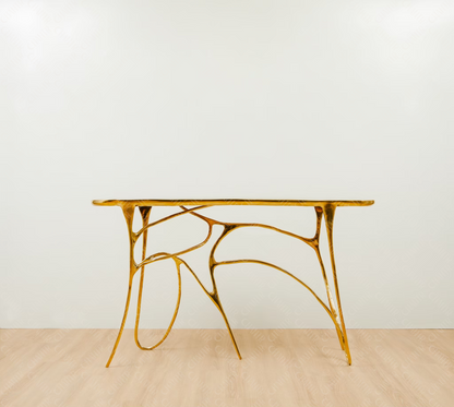 Gold brass luxury handmade furniture table with organic design, perfect for modern luxury decor, on a light wooden floor with white wall background.